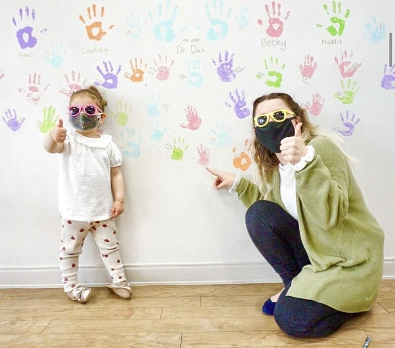 Child and adult giving thumbs up by handprints.
